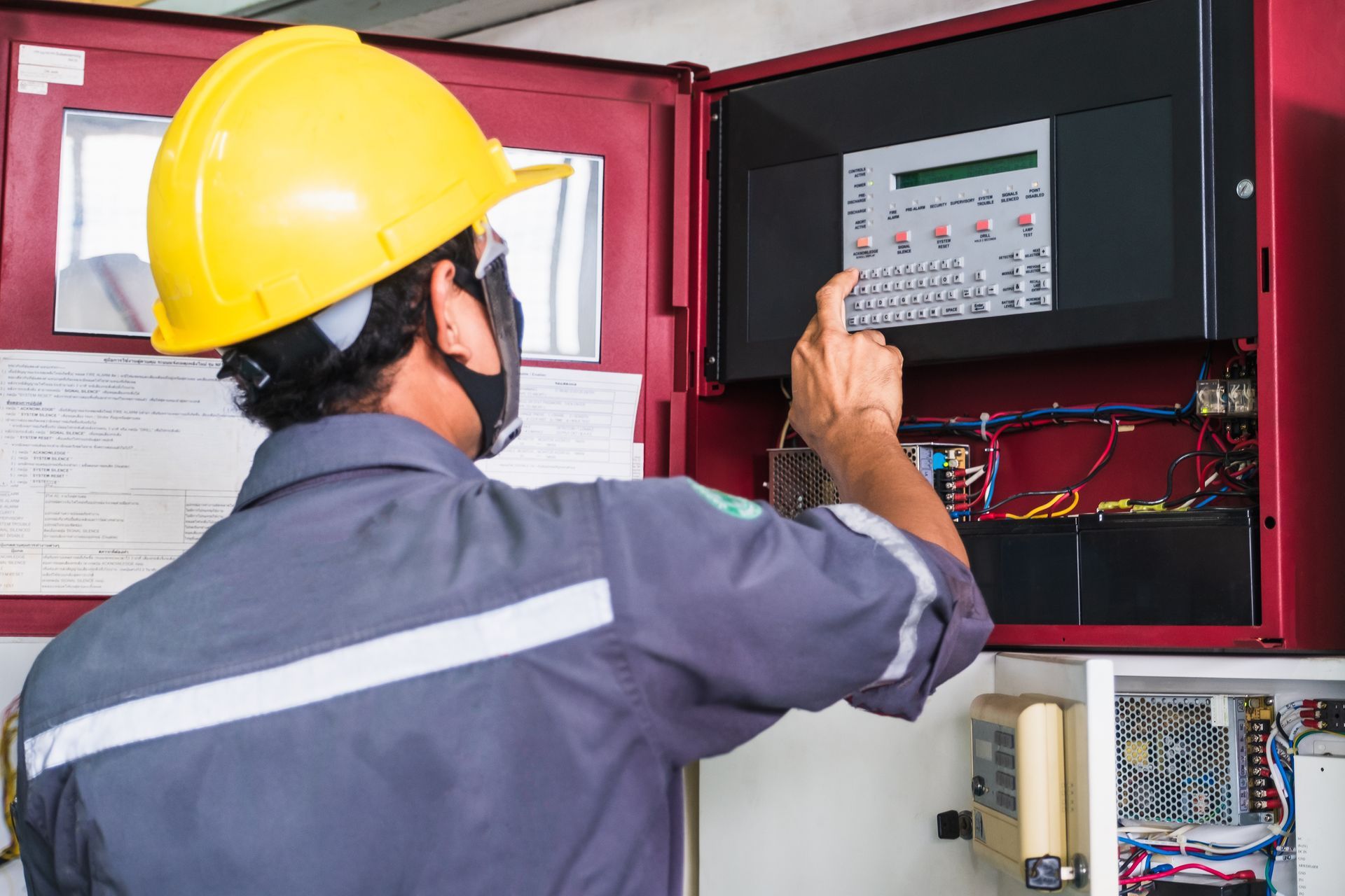 Technician conducting maintenance on a fire alarm system in a factory for fire protection and safety. 