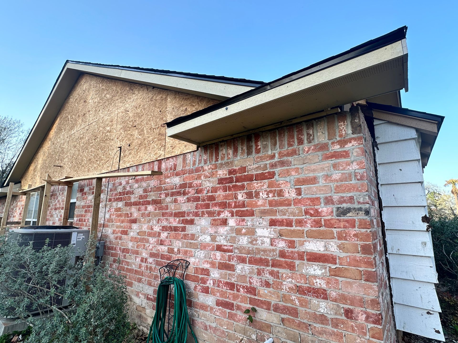 Brick building with exposed wood siding and roof against a blue sky.