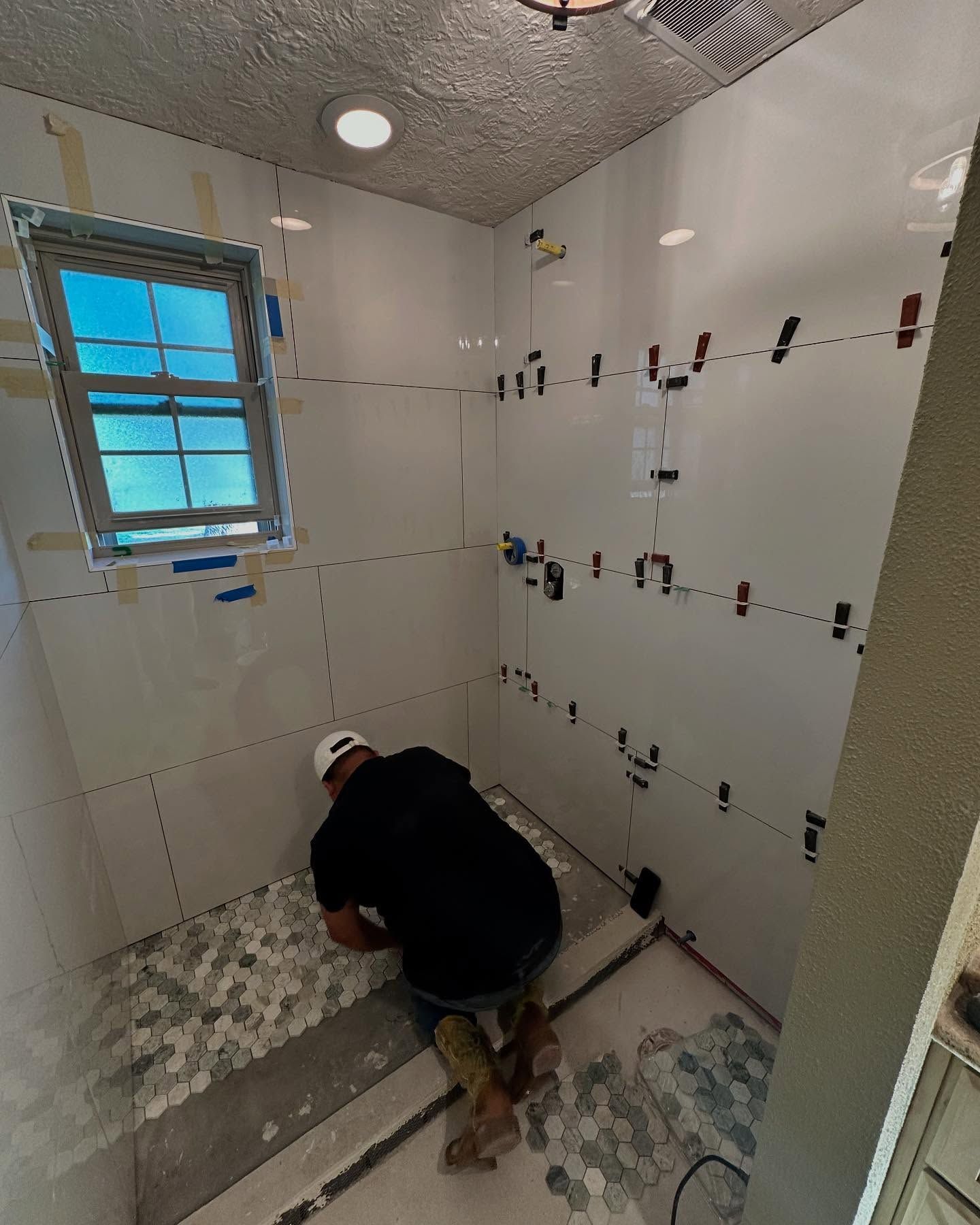 A man is working on a tiled floor in a bathroom