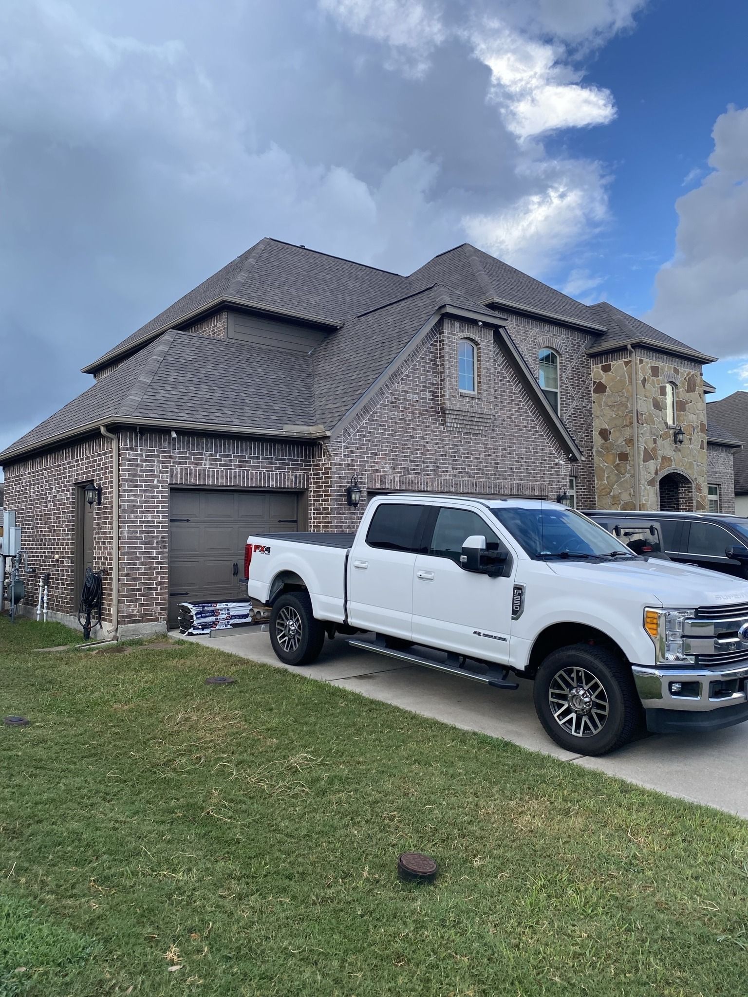 A white truck is parked in front of a large house.