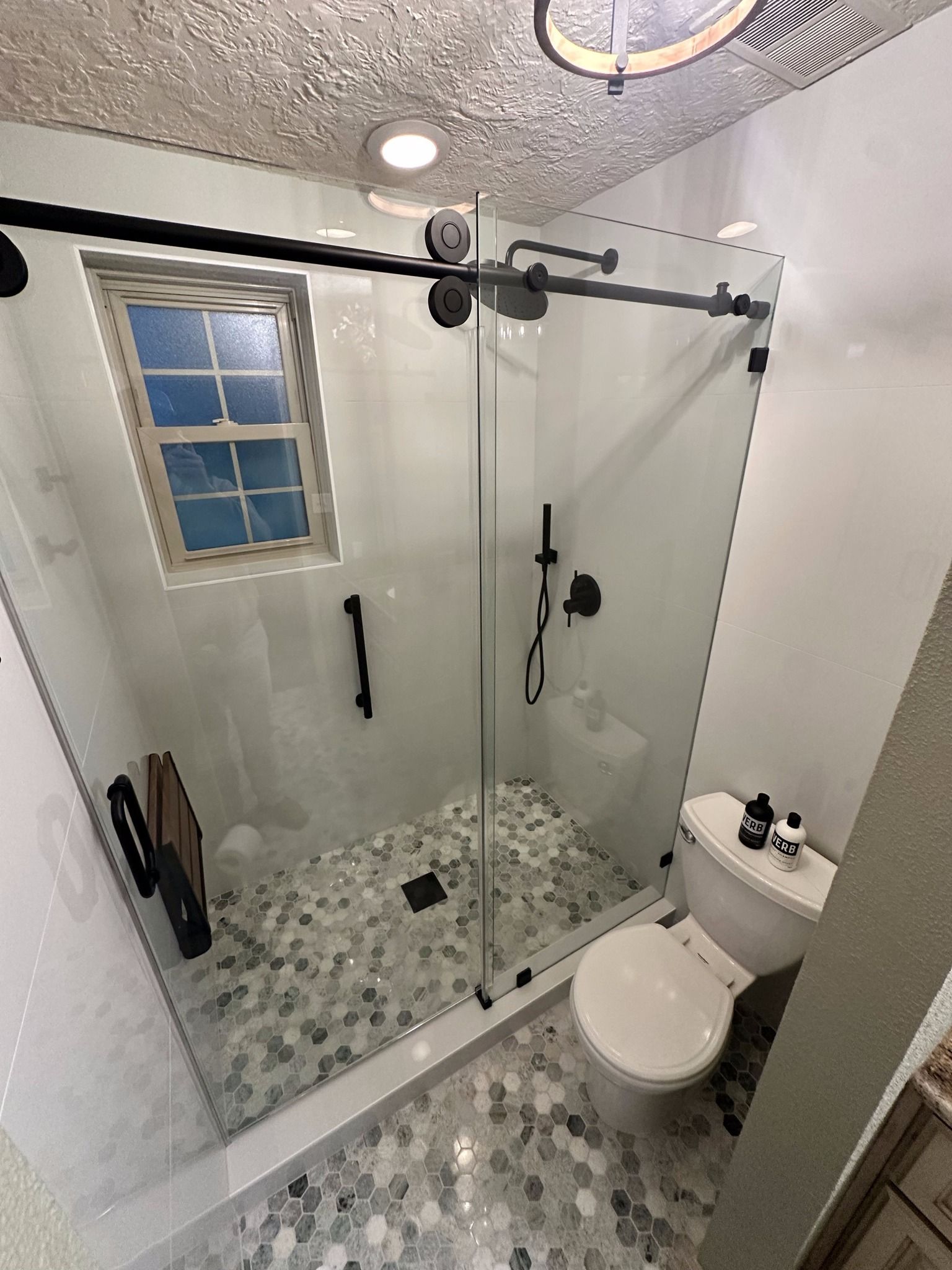 A bathroom with a sliding glass shower door and a toilet.