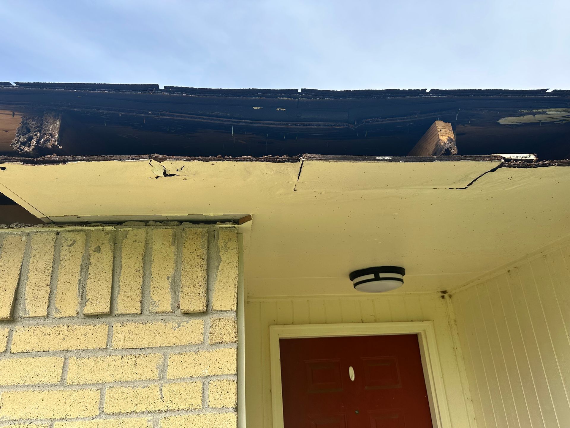 Damaged eaves of a building with exposed wood, showing signs of rot and wear.