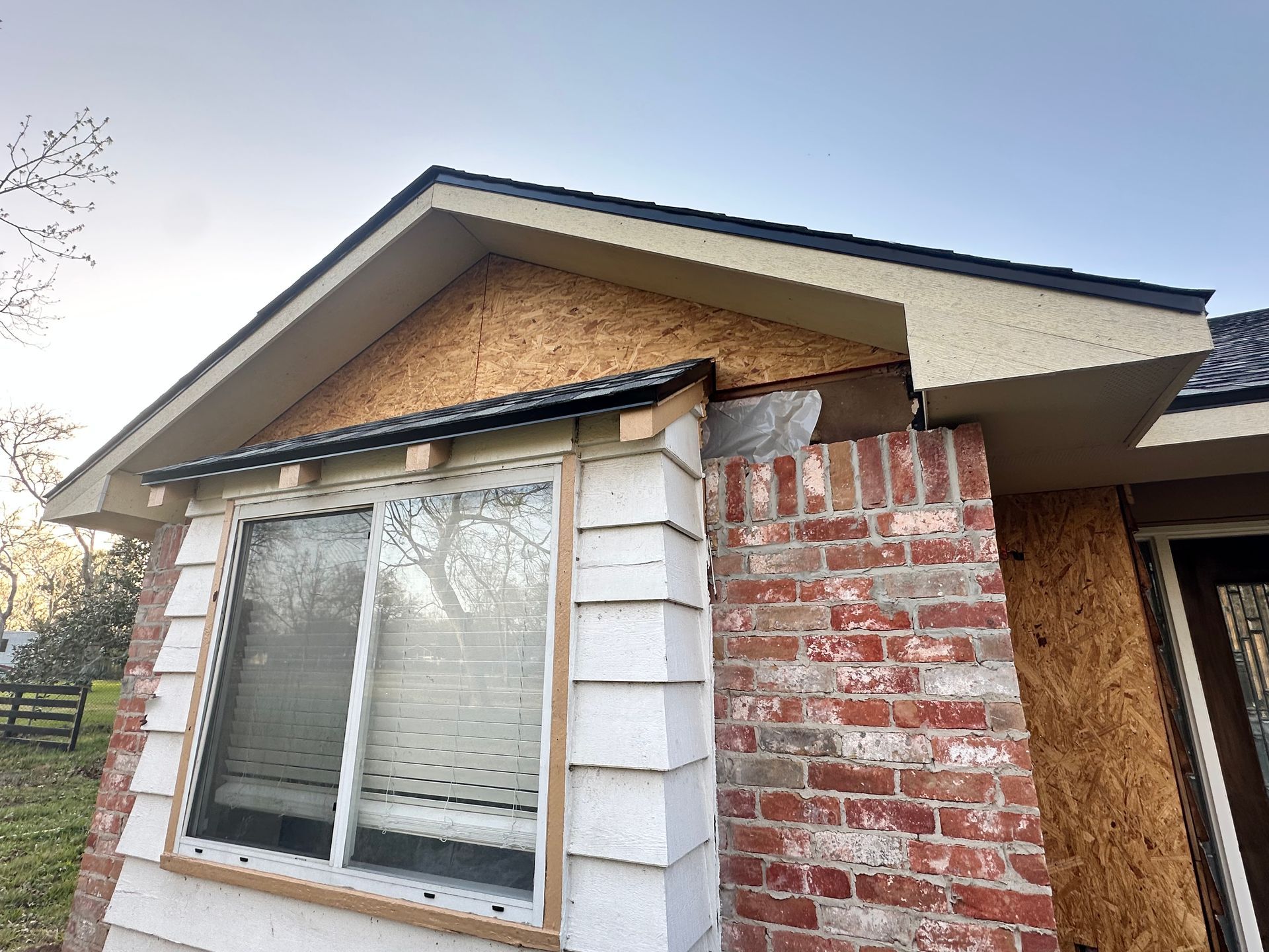 Construction in progress: Exterior view of a house with exposed OSB, brick, and white siding.