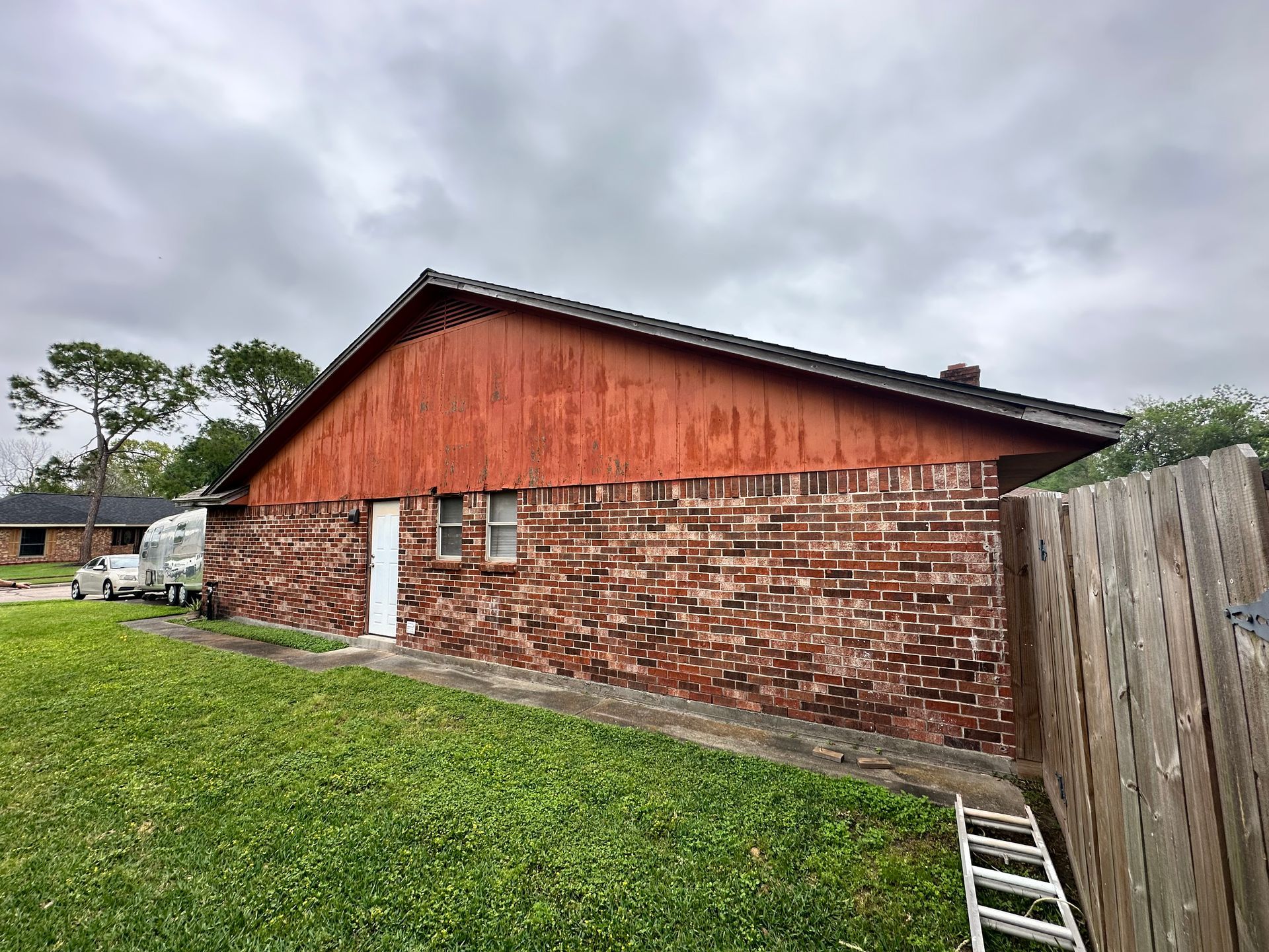 Red brick and wood building under cloudy sky, green lawn in front.