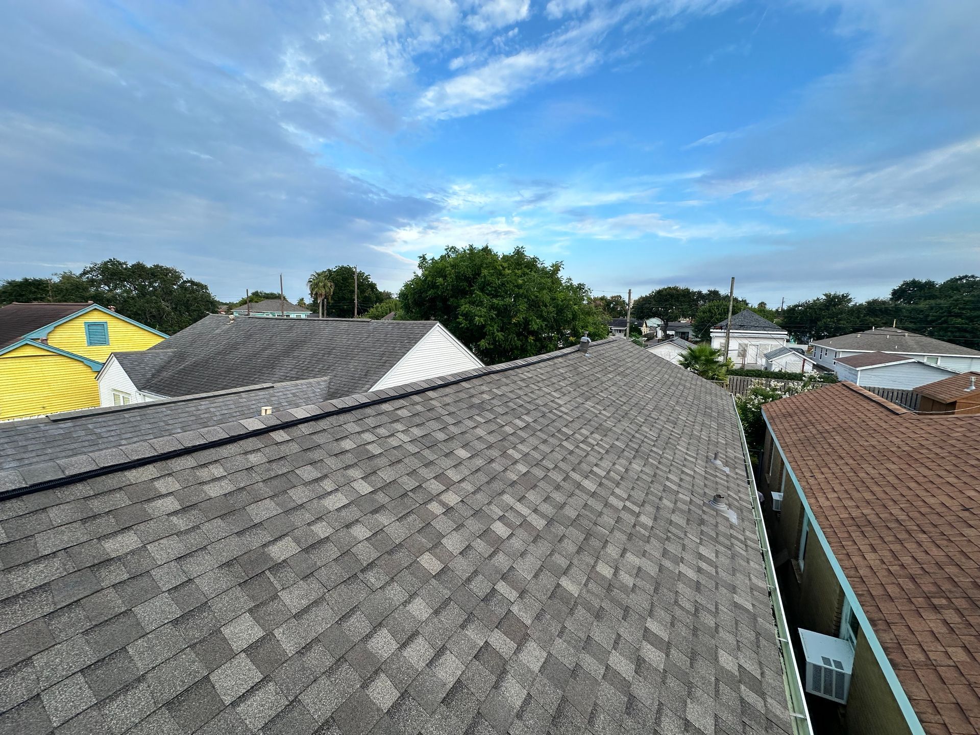 Rooftops of houses on a sunny day with blue sky and some clouds.
