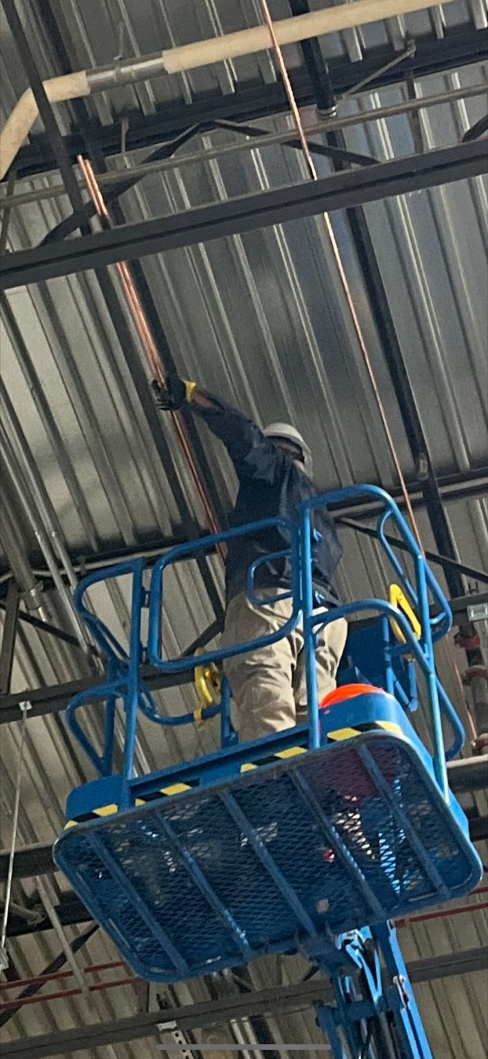 A man is standing on a lift working on the ceiling of a building.