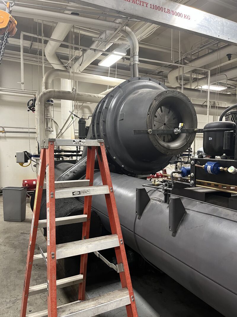 A ladder is sitting next to a large machine in a factory.