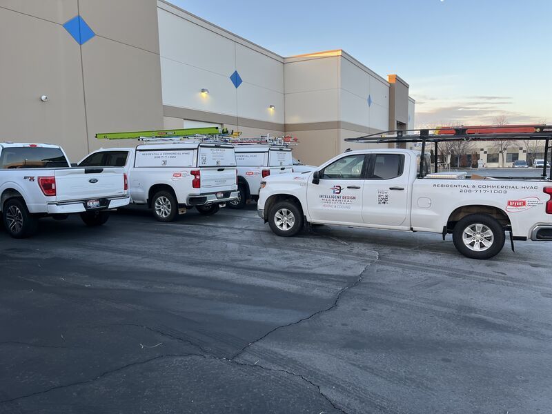 A row of white trucks are parked in front of a building.