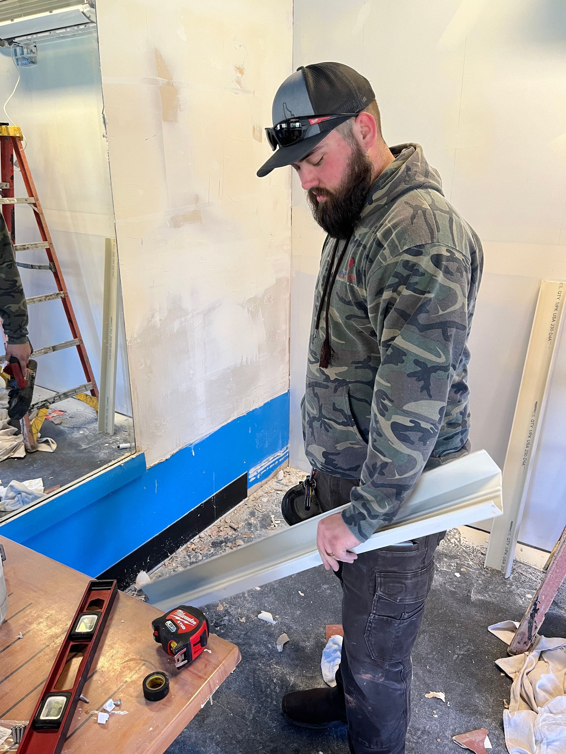 A man with a beard is standing in a room holding a tool.
