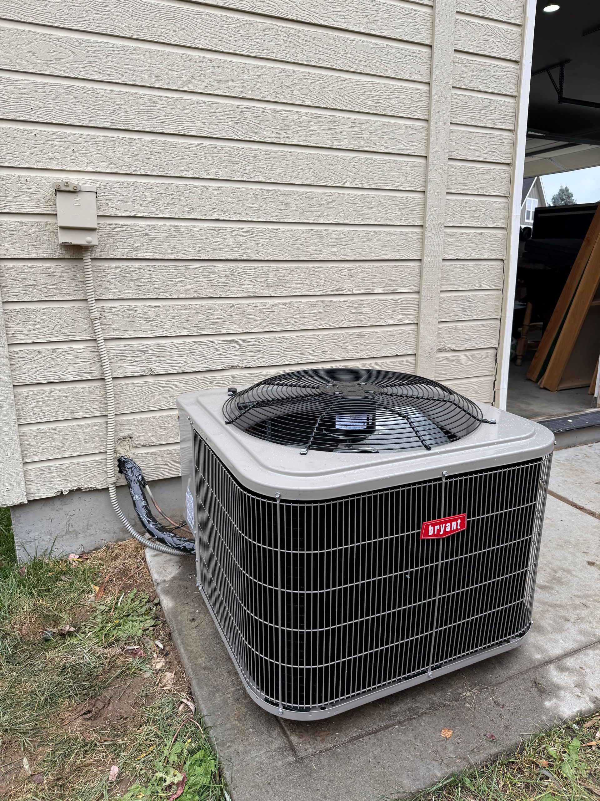 A large air conditioner is sitting outside of a brick building.