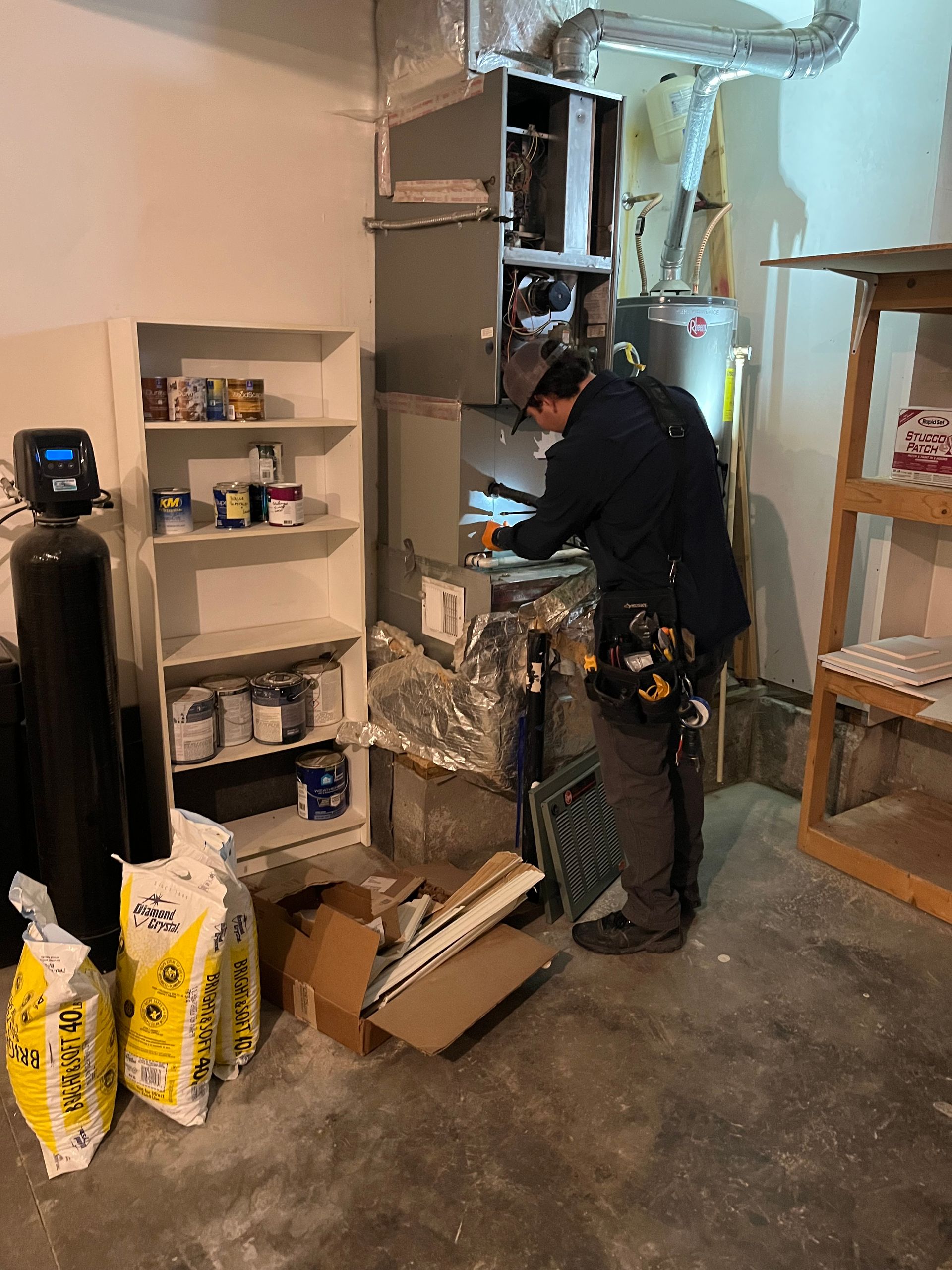 A man is working on an air conditioner in a garage.