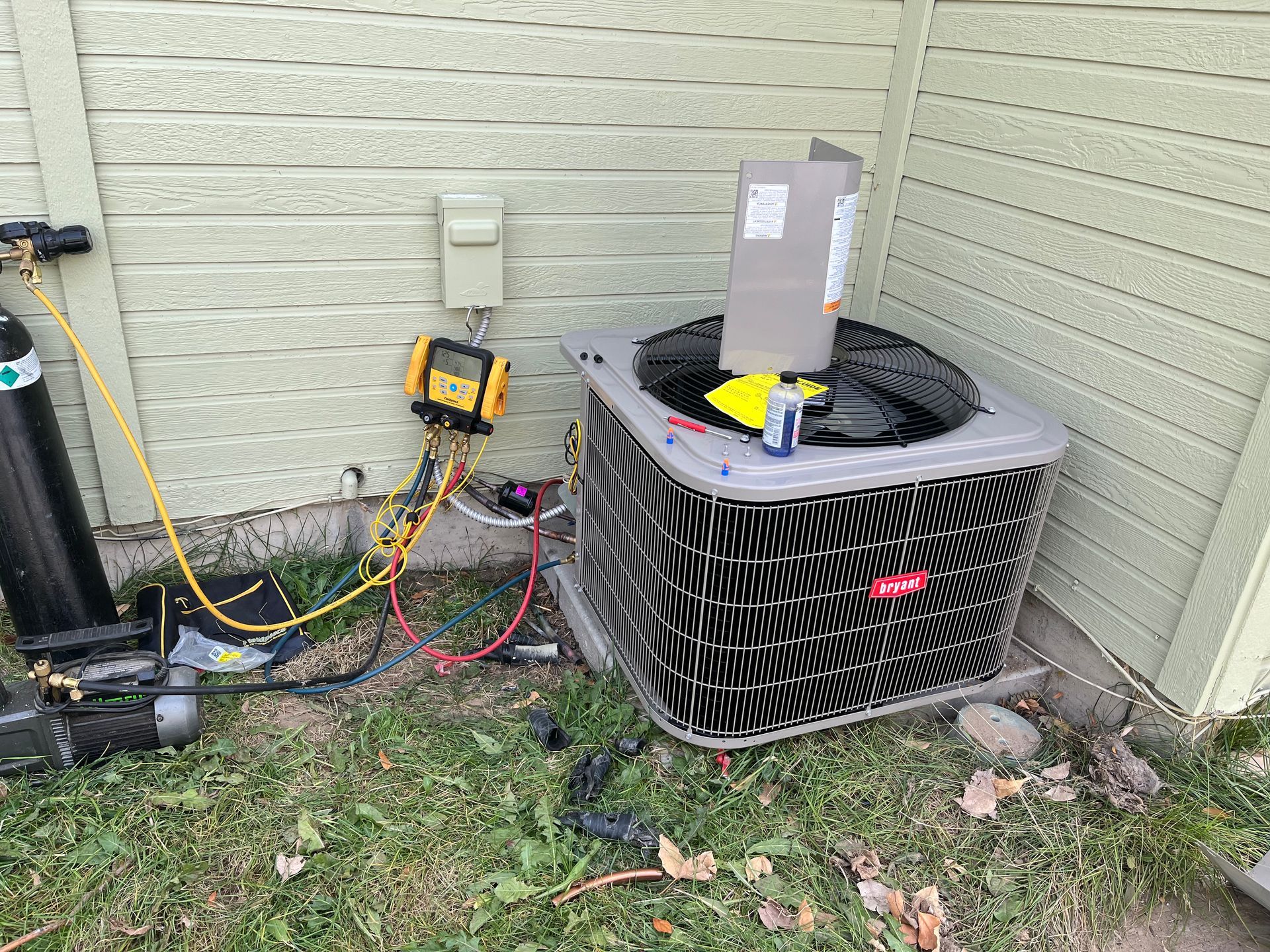 An air conditioner is being repaired outside of a house.
