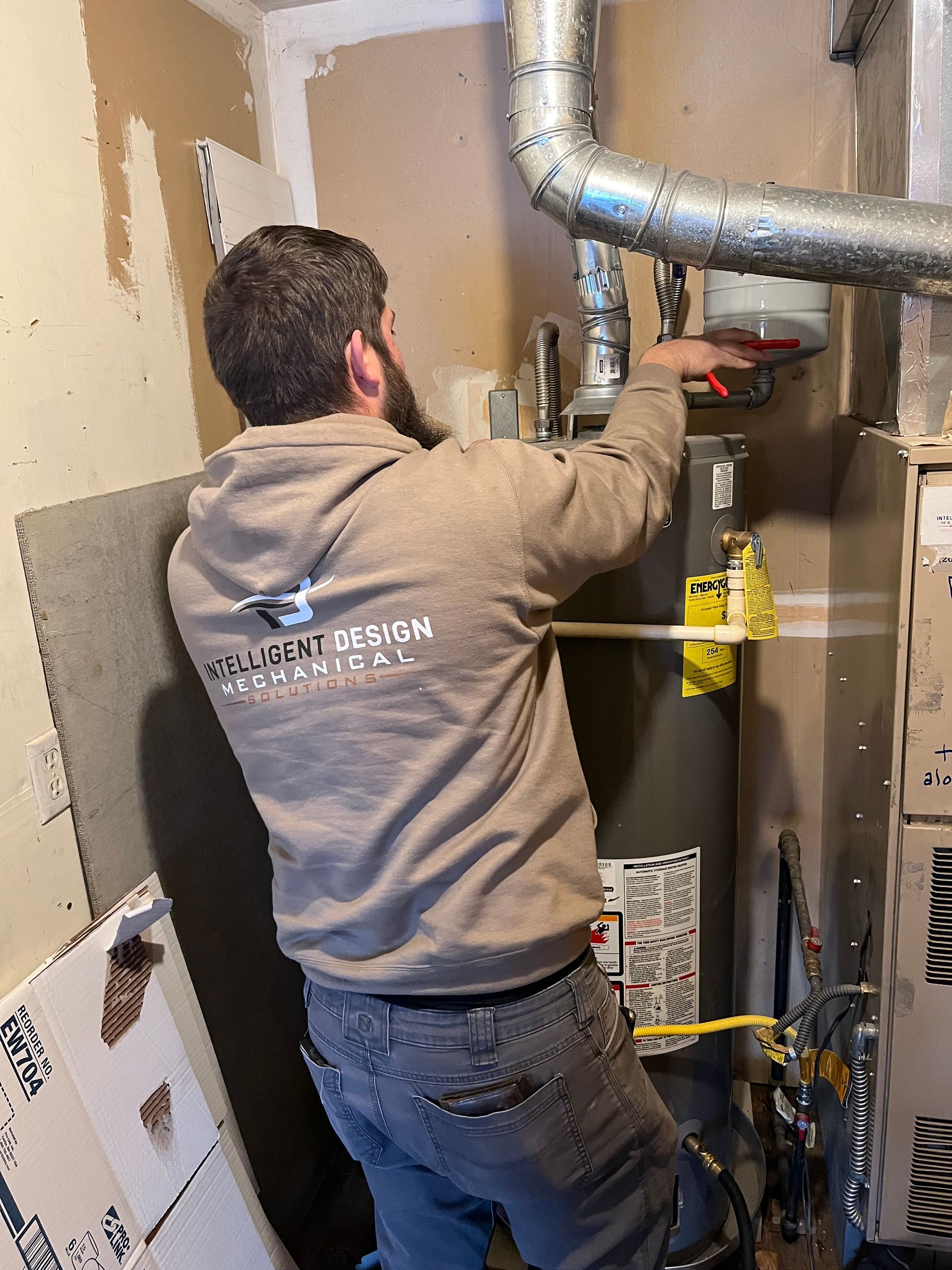 A man is measuring a water heater with a tape measure.