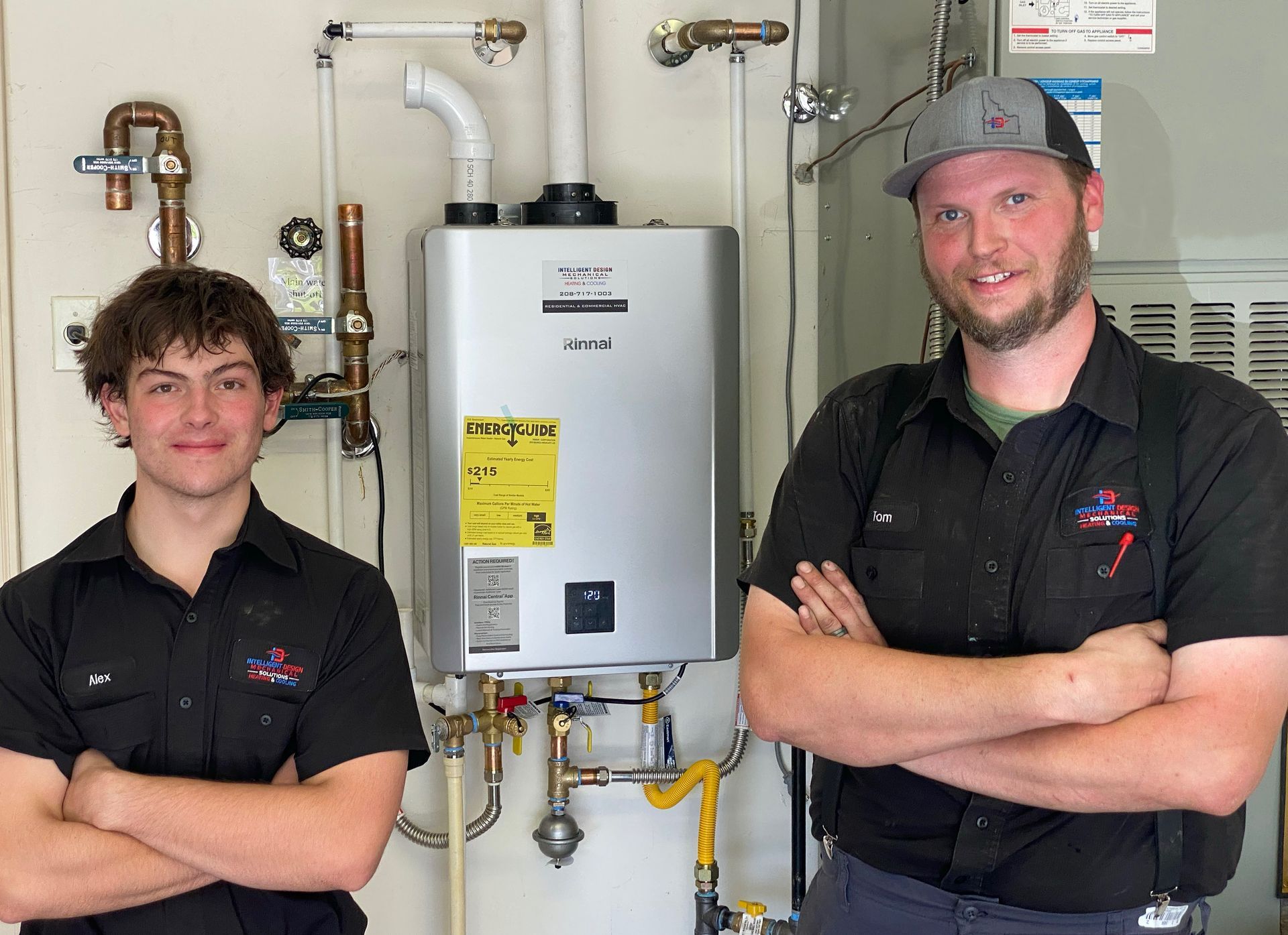 Two men are standing next to each other in front of a water heater.