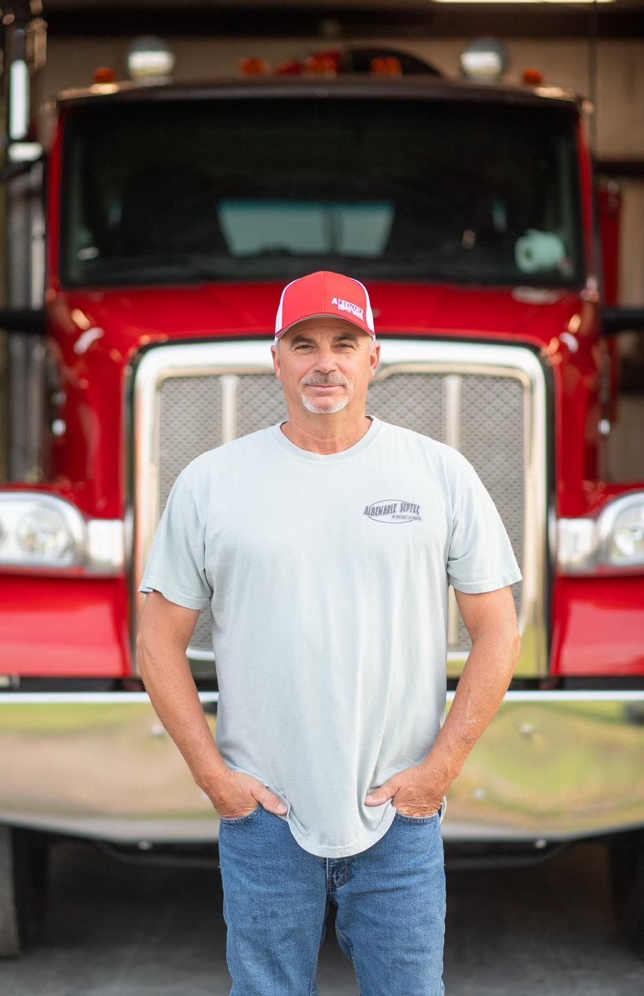 A man in a white shirt and hat is giving a thumbs up.