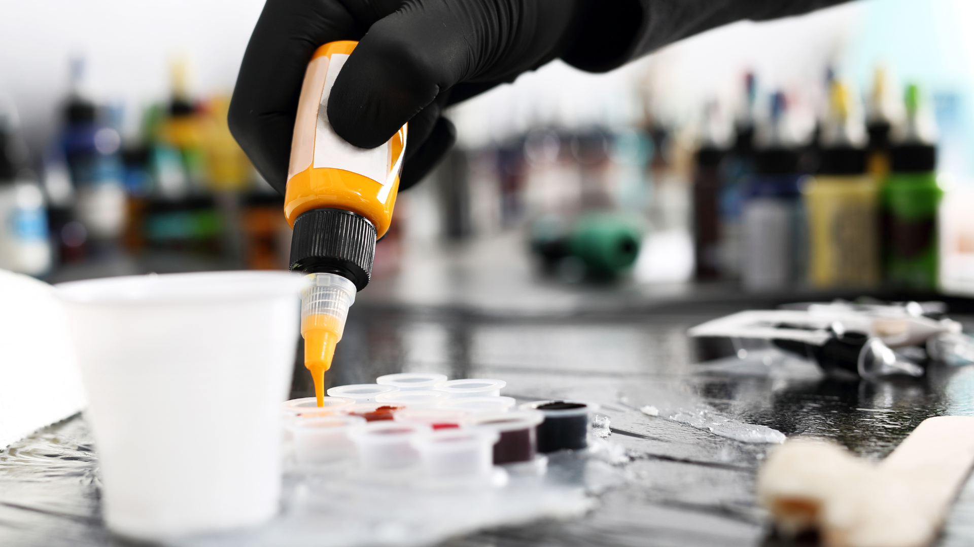 A person is pouring tattoo ink into a cup.