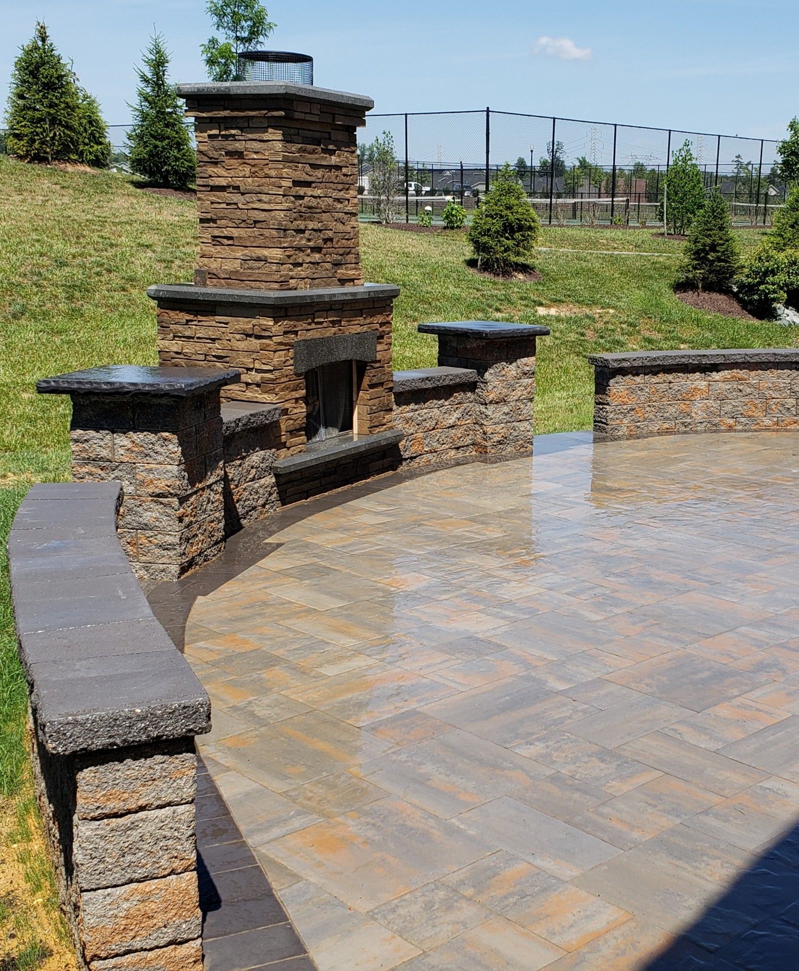 There is a stone fireplace on the side of the patio.