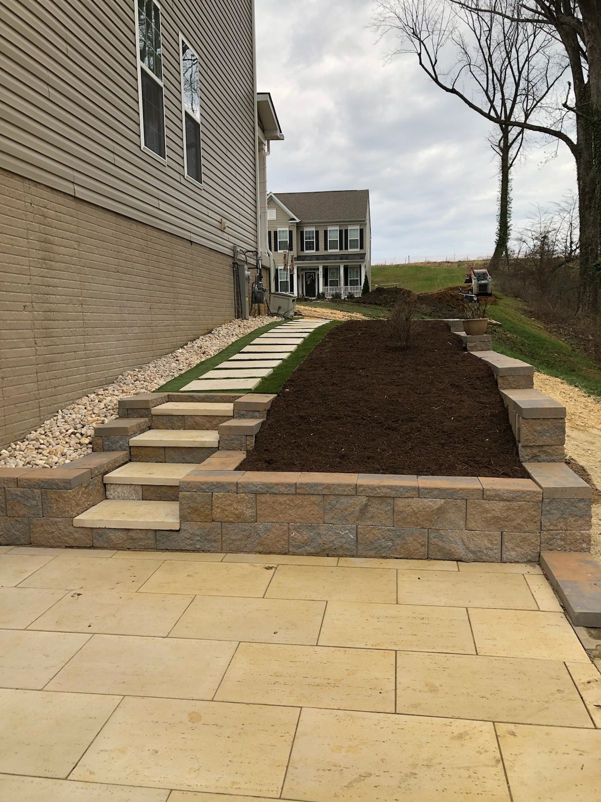 A brick walkway leading to a house with steps leading up to it.
