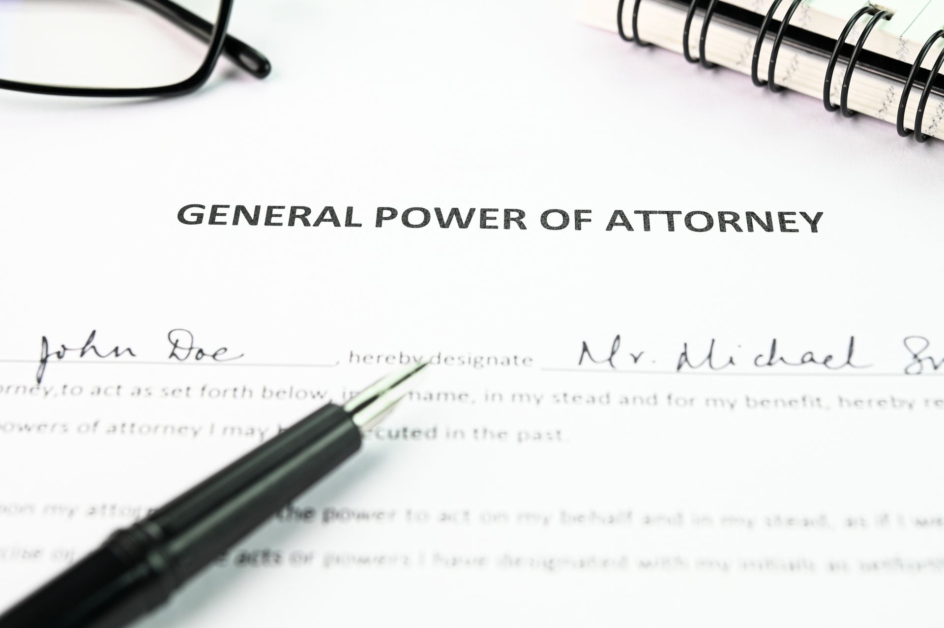 General Power of Attorney form with signatures, pen, glasses, and spiral notebook.