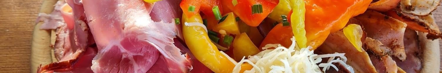 Sitzgelegenheiten im Schlossheurigen Vösendorf im Freien mit Holztischen, geflochtenen Stühlen und Bäumen, die Schatten spenden.