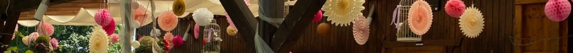 Sitzgelegenheiten im Schlossheurigen Vösendorf im Freien mit Holztischen, geflochtenen Stühlen und Bäumen, die Schatten spenden.