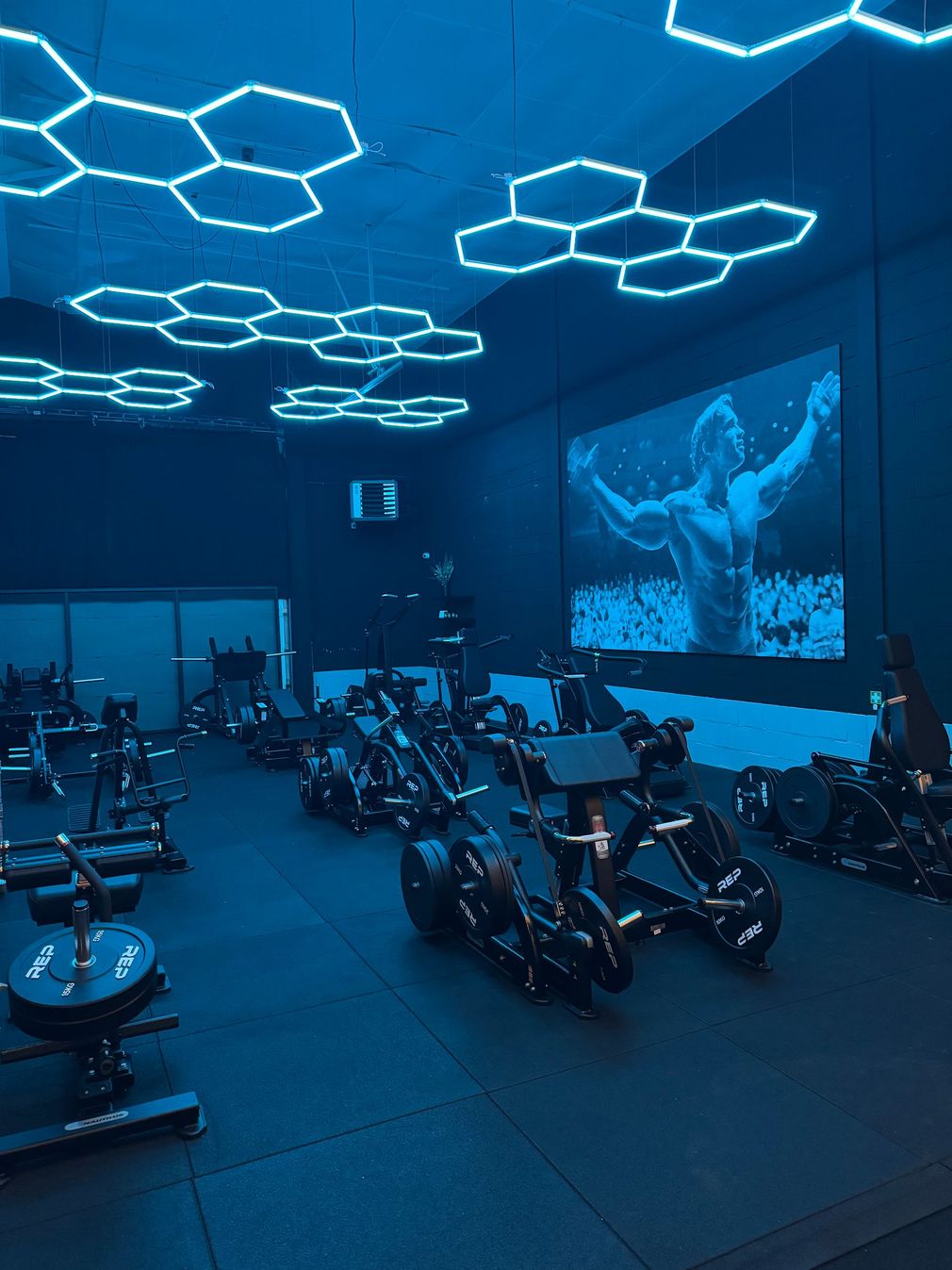 Een sportschool met veel fitnessapparatuur en led-verlichting.