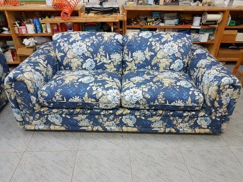 un divano rivestito in una stoffa di color blu con dei disegni a fiori