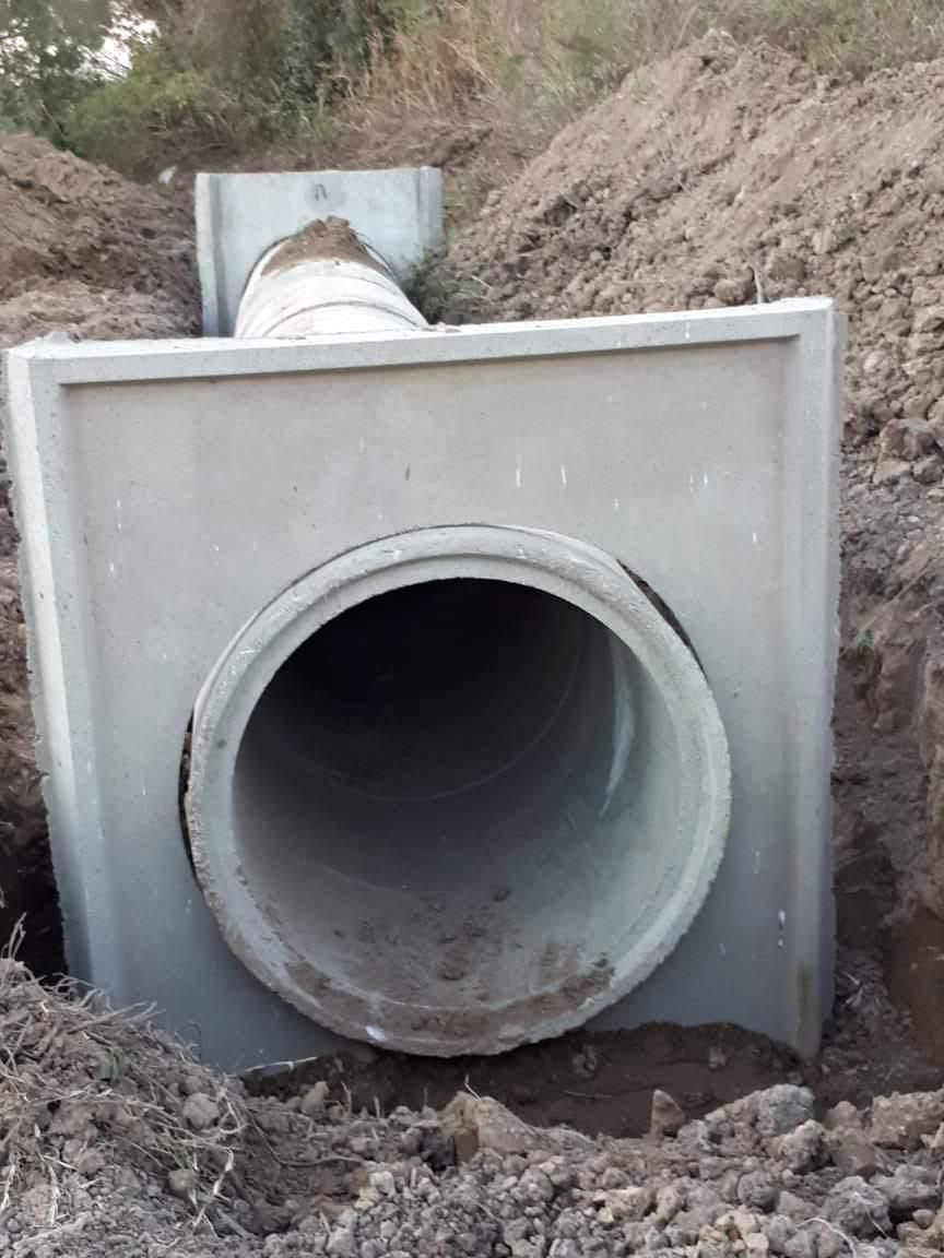 Sección de tubería de alcantarillado de hormigón en una zanja de tierra, lista para su instalación.