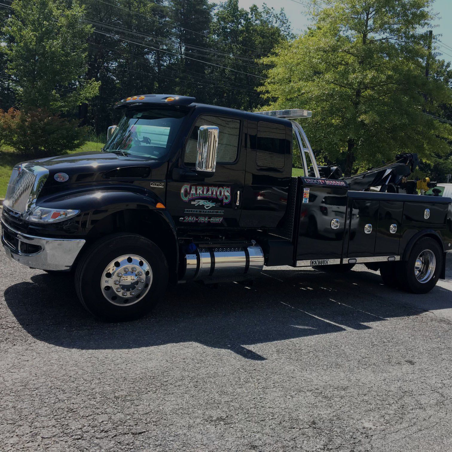 A black tow truck is parked on the side of the road.