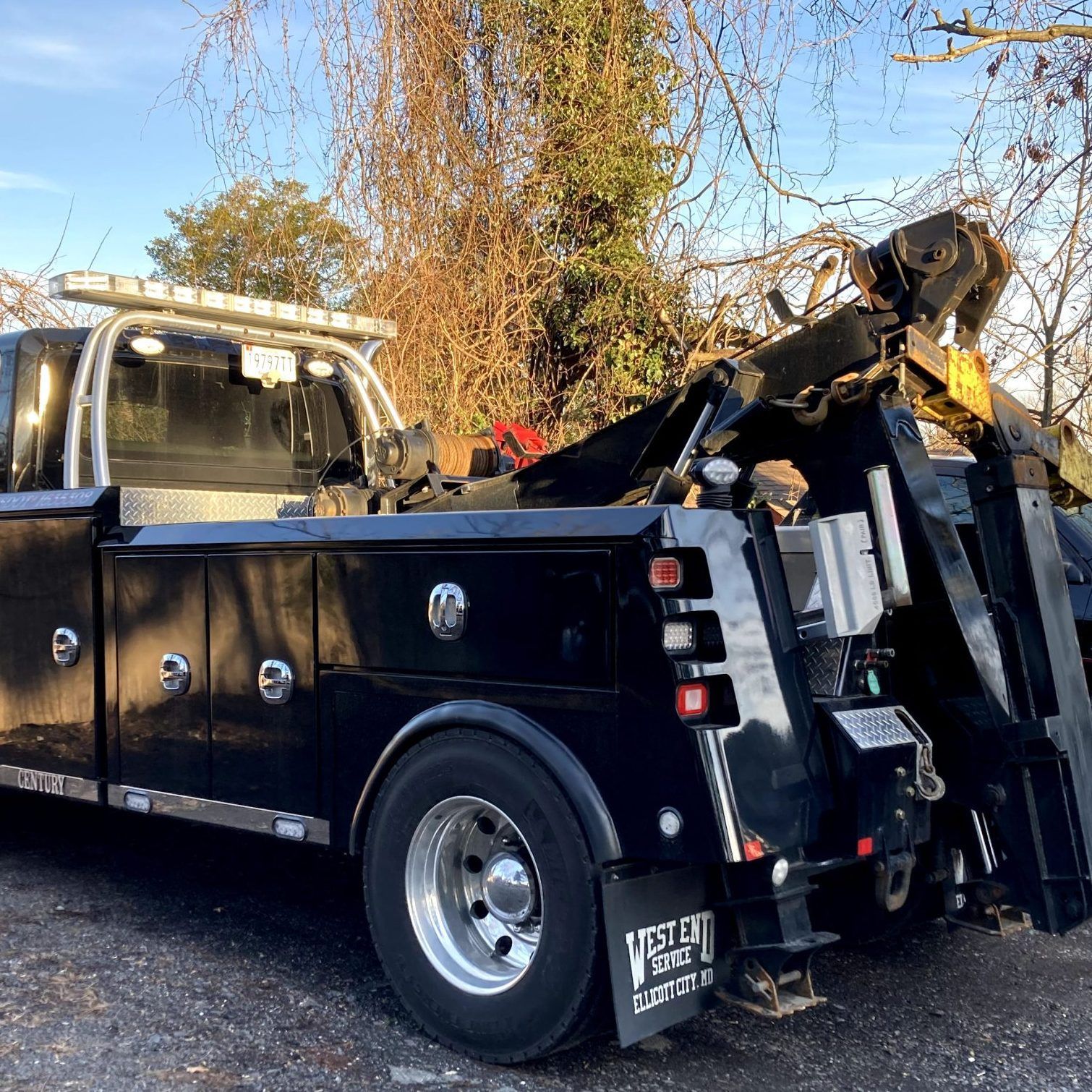 A black tow truck is parked in a parking lot.