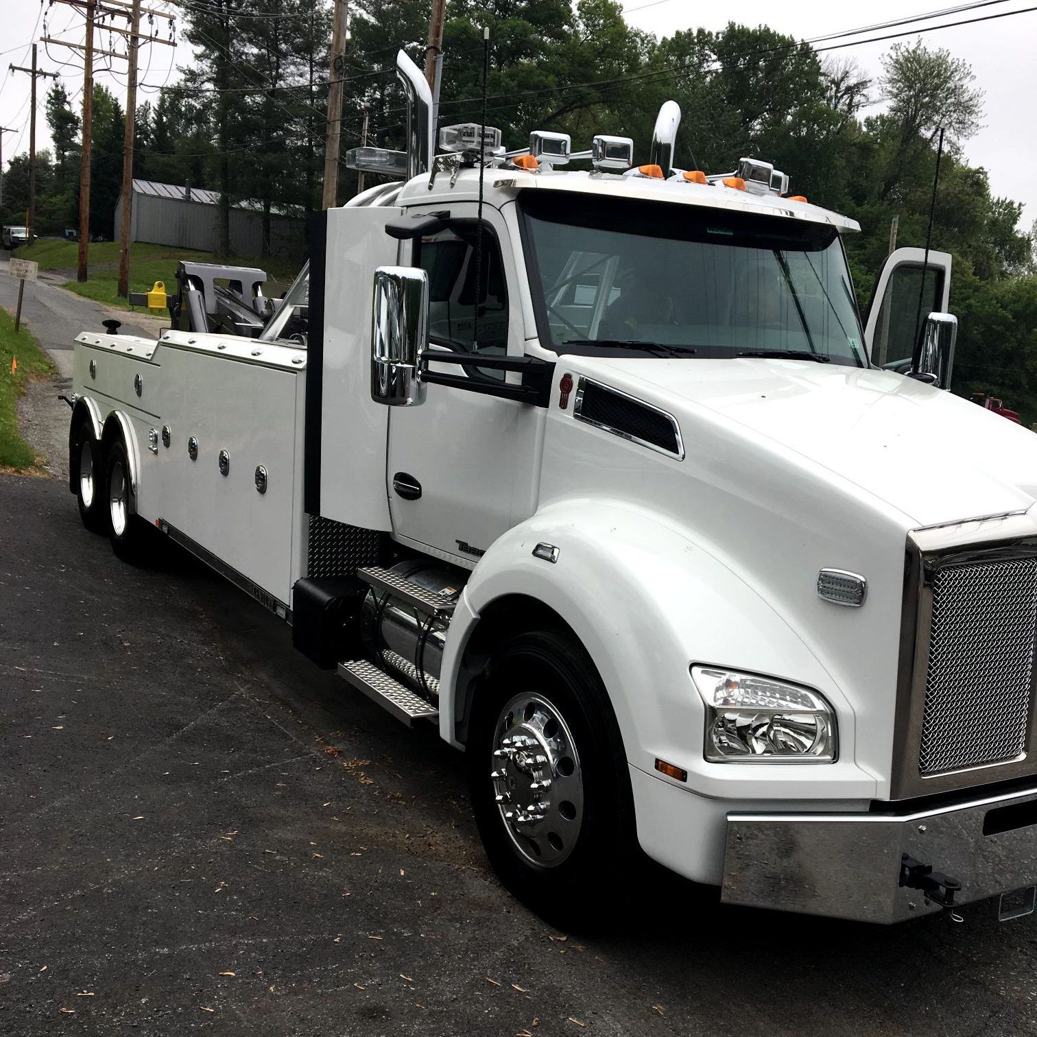 A white tow truck is parked on the side of the road