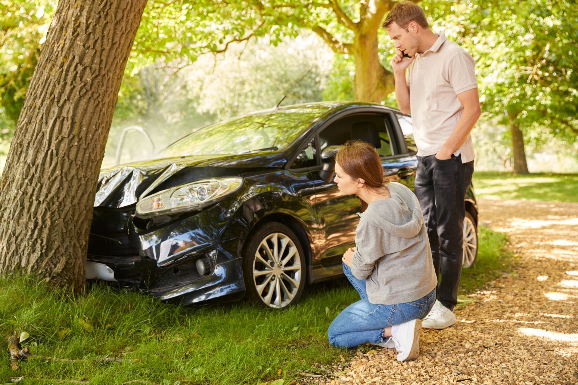 A man and a woman are standing next to a damaged car.
