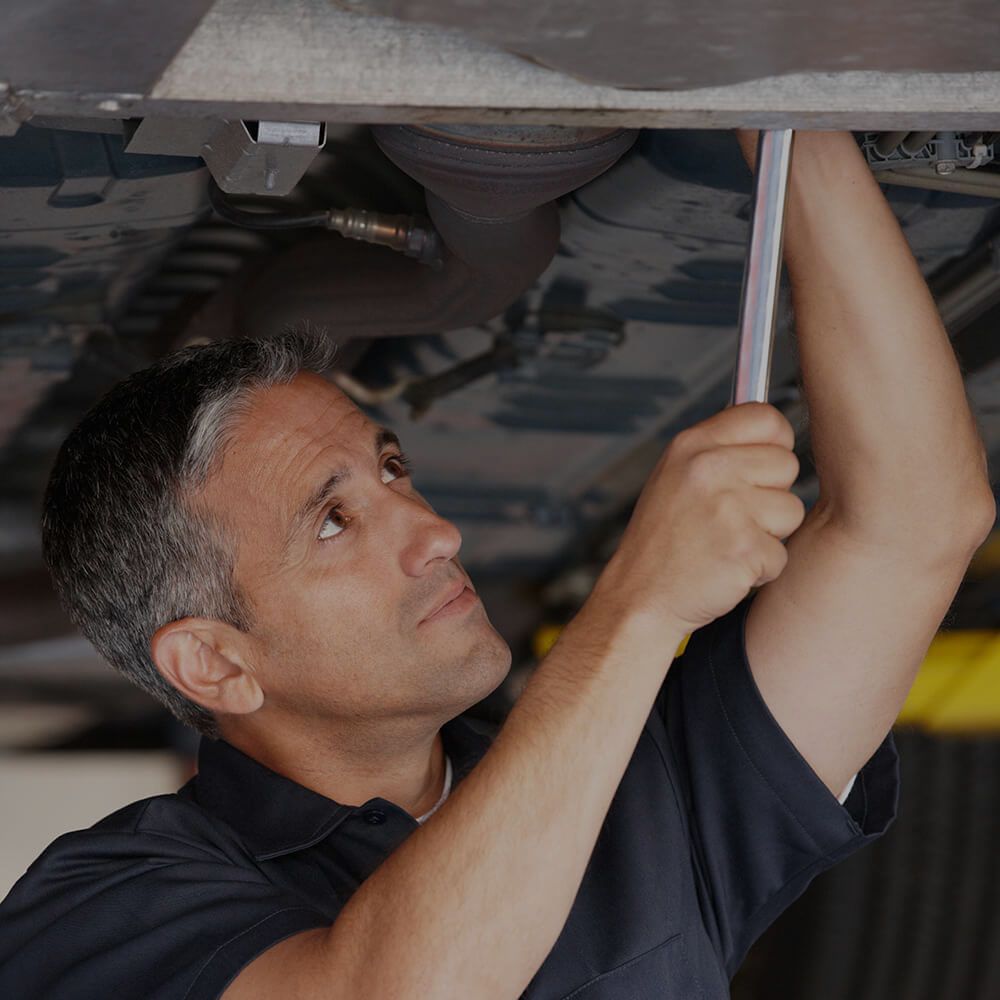 A man is working under a car with a wrench