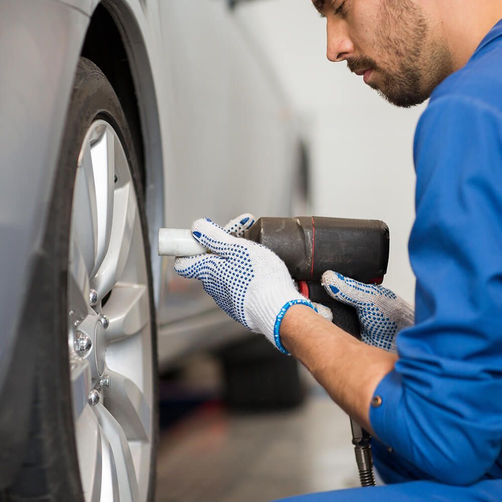 A man in a blue uniform is working on a tire