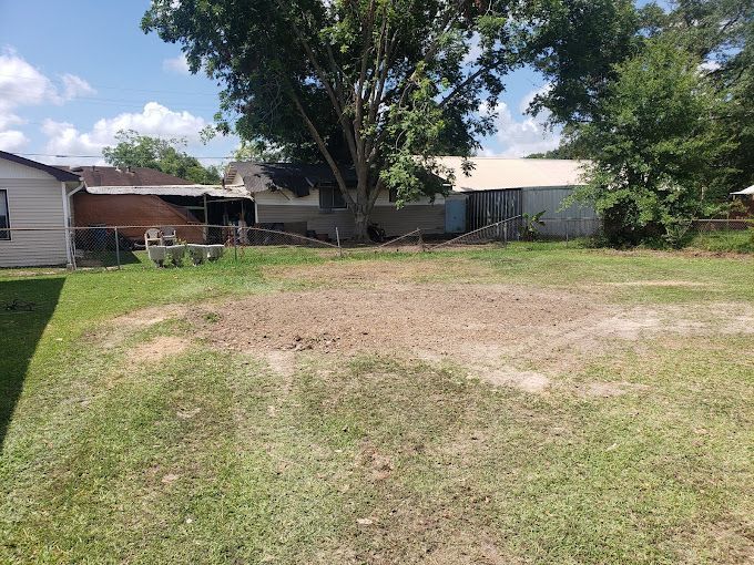 There is a lot of grass and dirt in the backyard of a house.