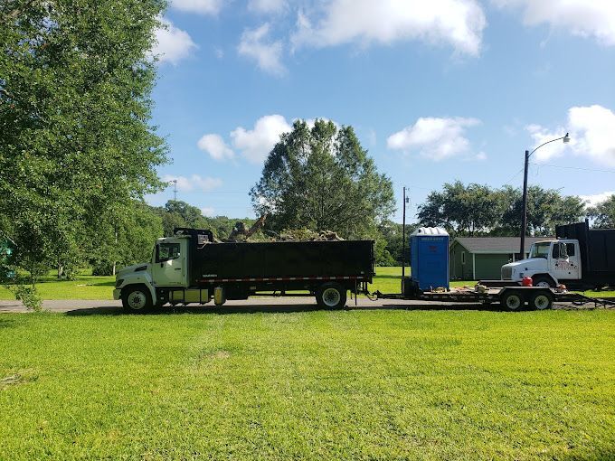 A dump truck with a trailer attached to it is parked in a grassy field.