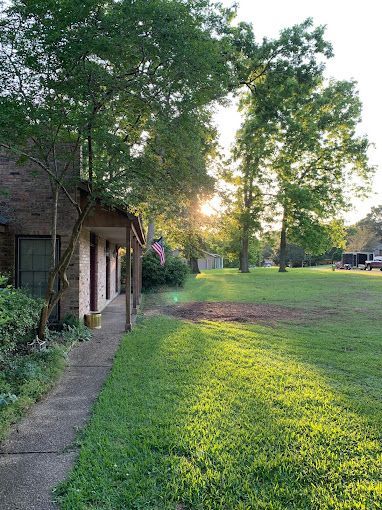 A house with a porch and a large lawn in front of it.