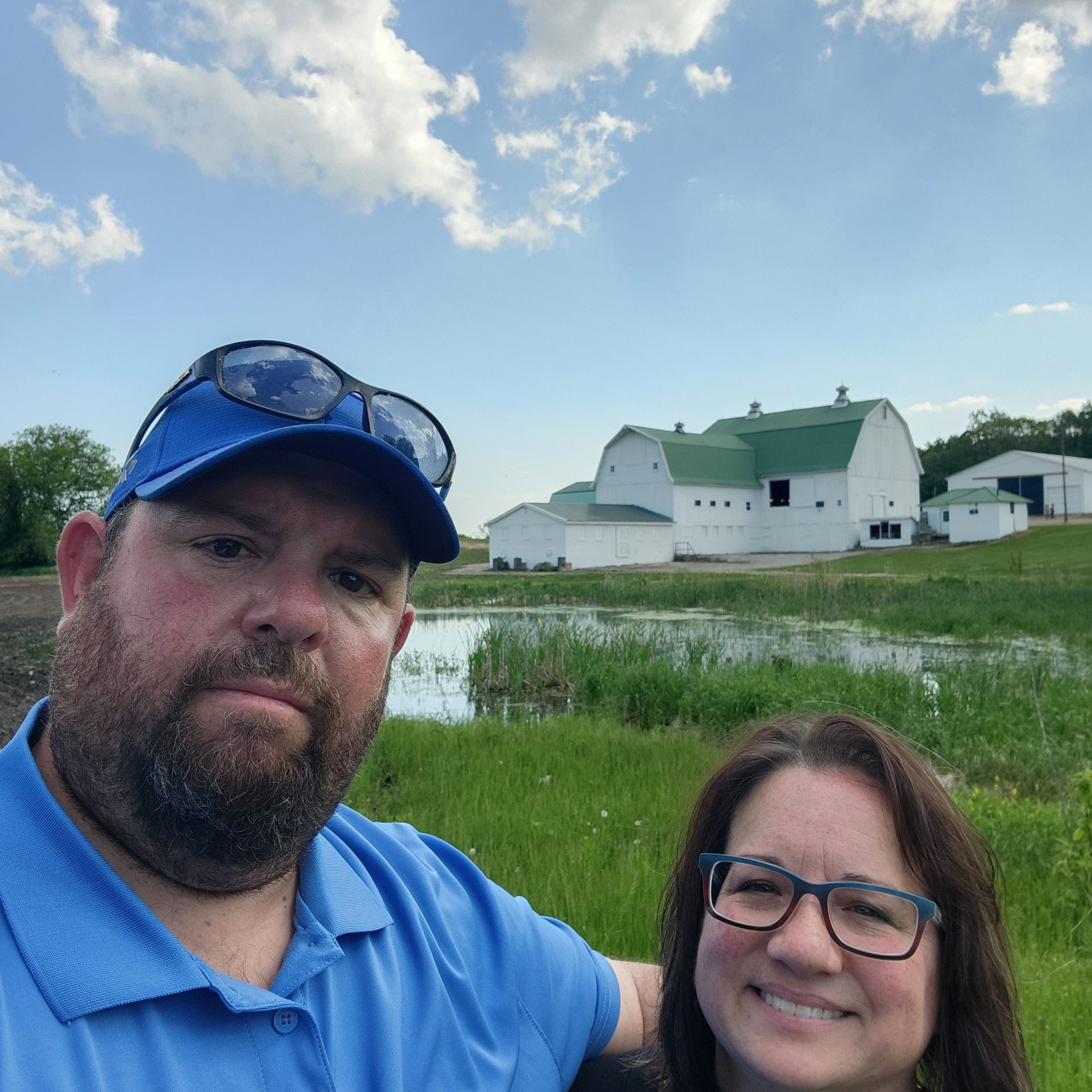A man and a woman are posing for a picture in front of a barn.