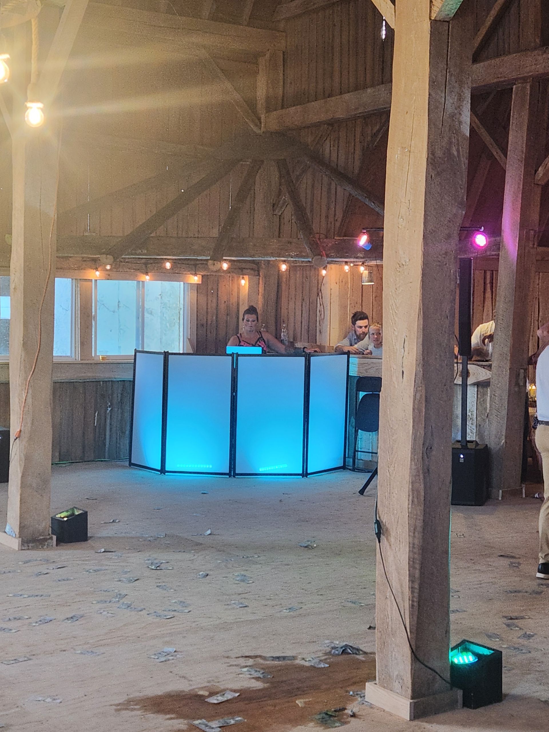 A dj is playing music at a wedding reception in a barn.