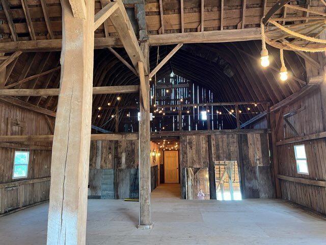 The inside of an old barn with wooden beams and windows.