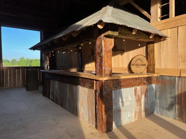 A wooden bar in a barn with a tin roof.