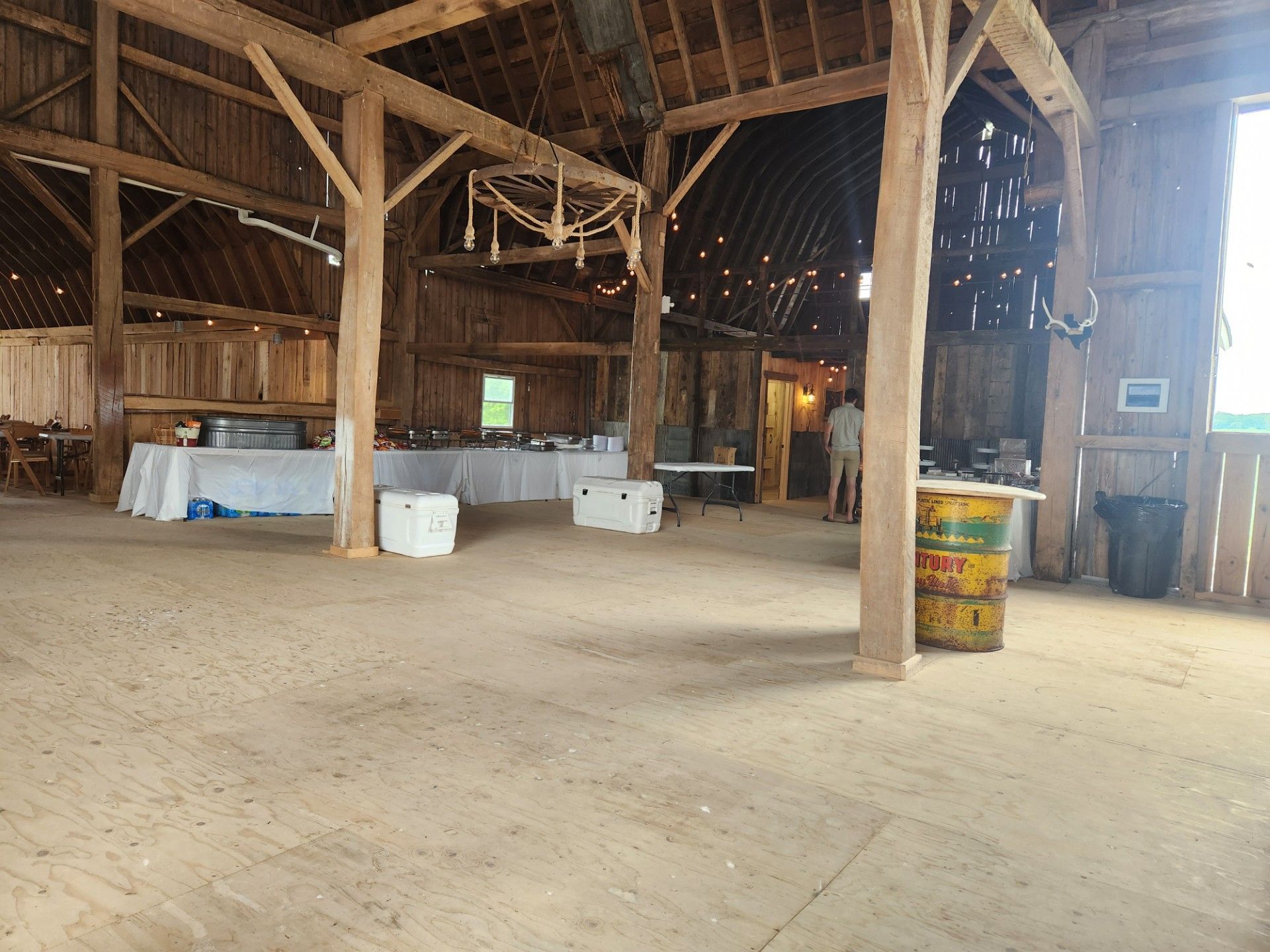 An empty barn with tables and barrels in it