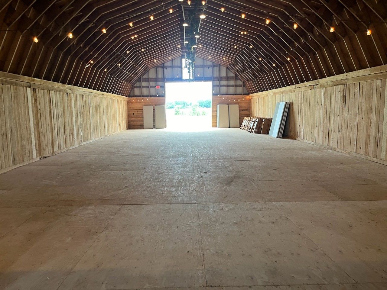 A large empty barn with a large door open.