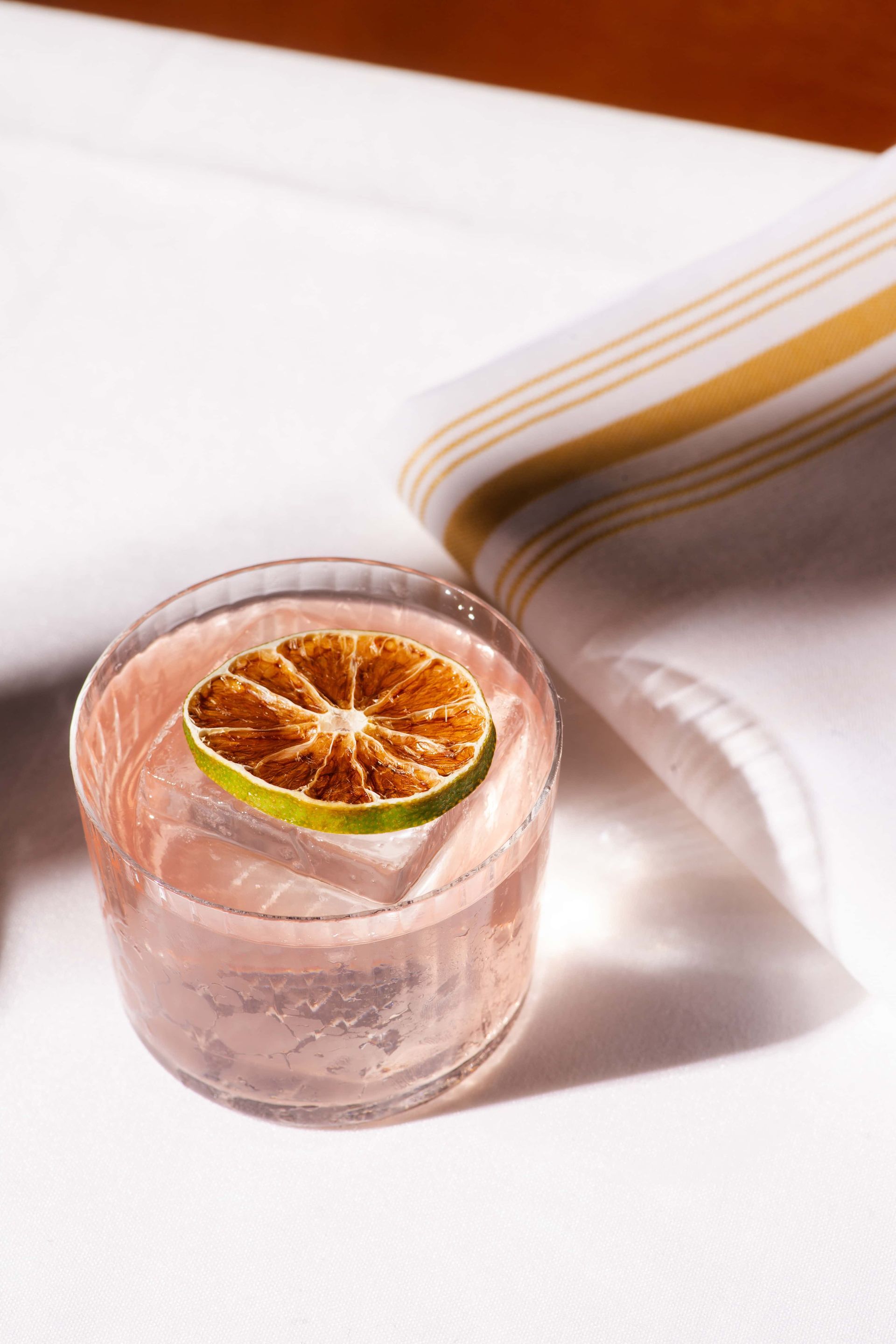 A glass of pink liquid with a slice of lime in it