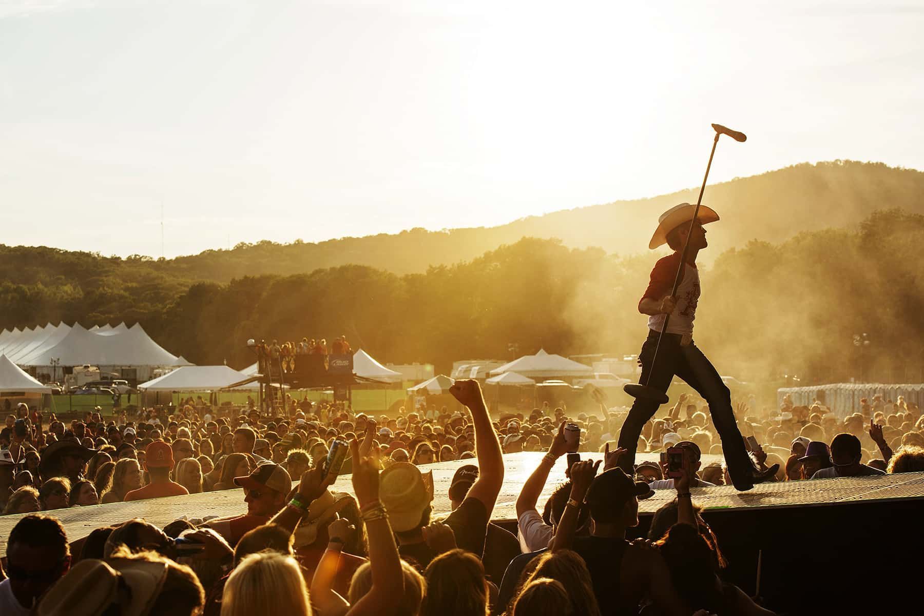 A man in a cowboy hat is standing on a stage holding a microphone.