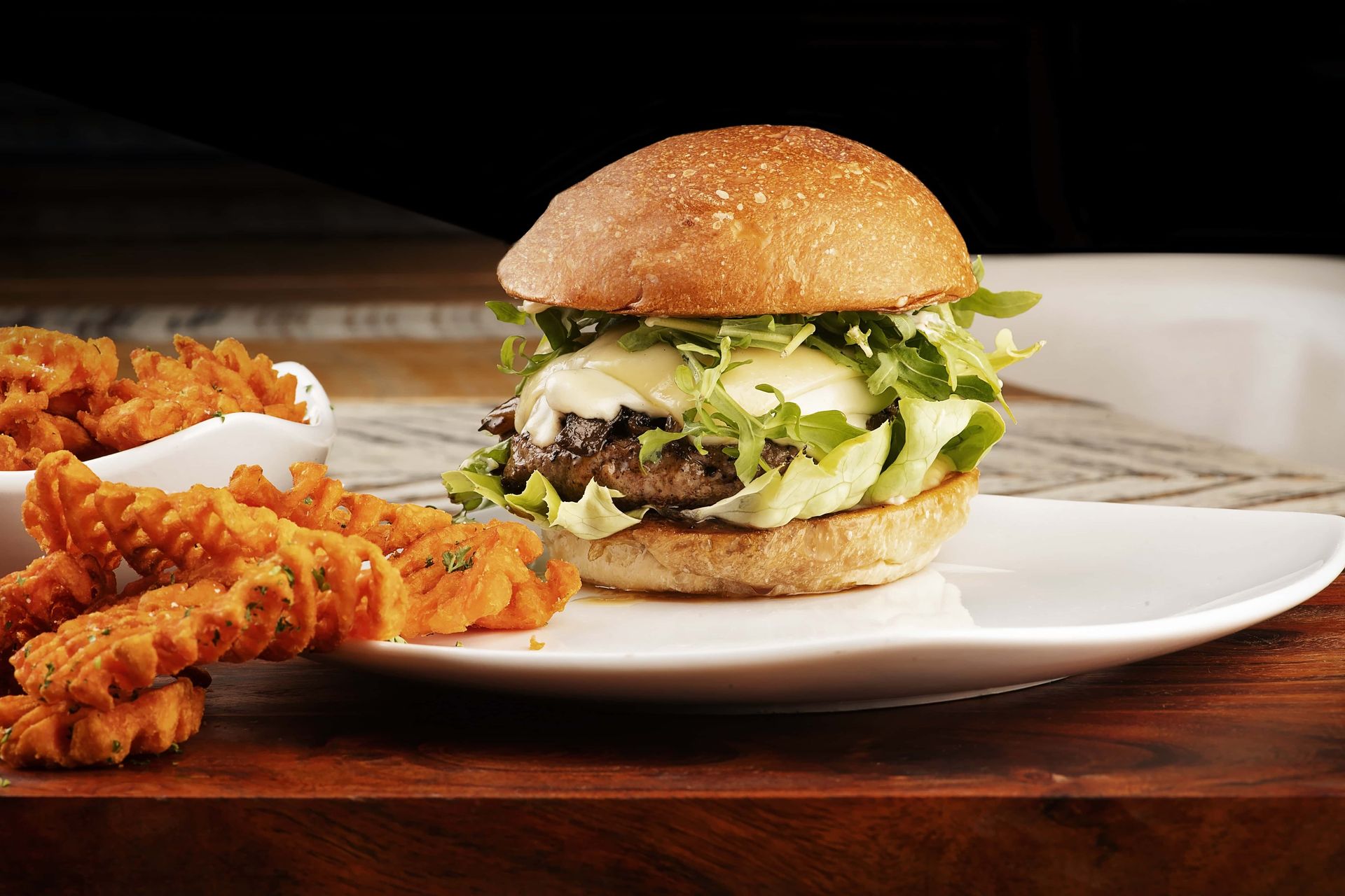 A white plate topped with a hamburger and sweet potato fries