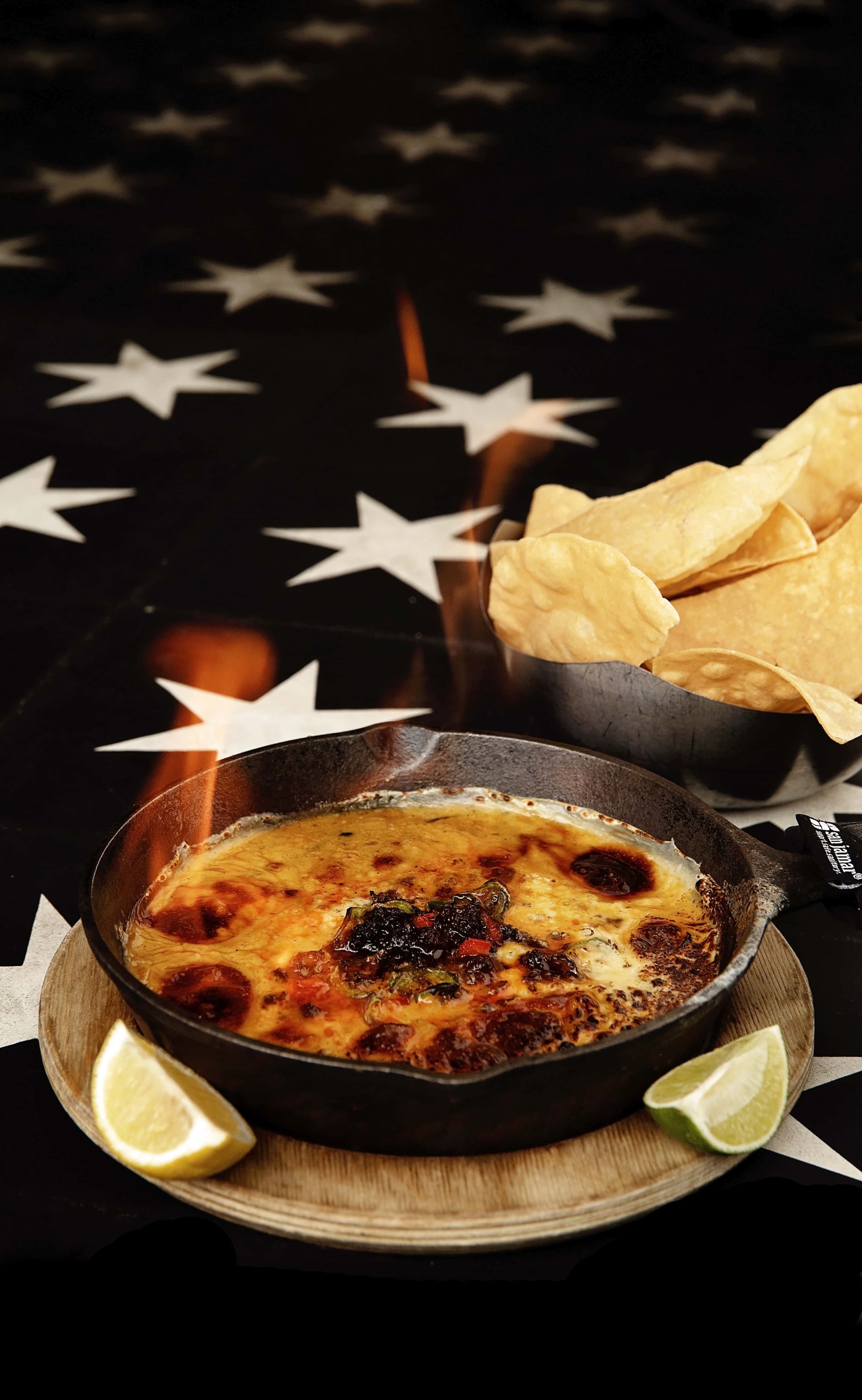 A bowl of food is sitting on a table next to a bowl of tortilla chips.