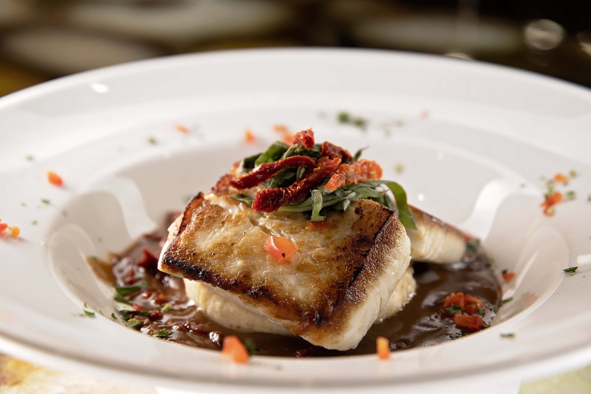 A white plate topped with a piece of meat and sauce.