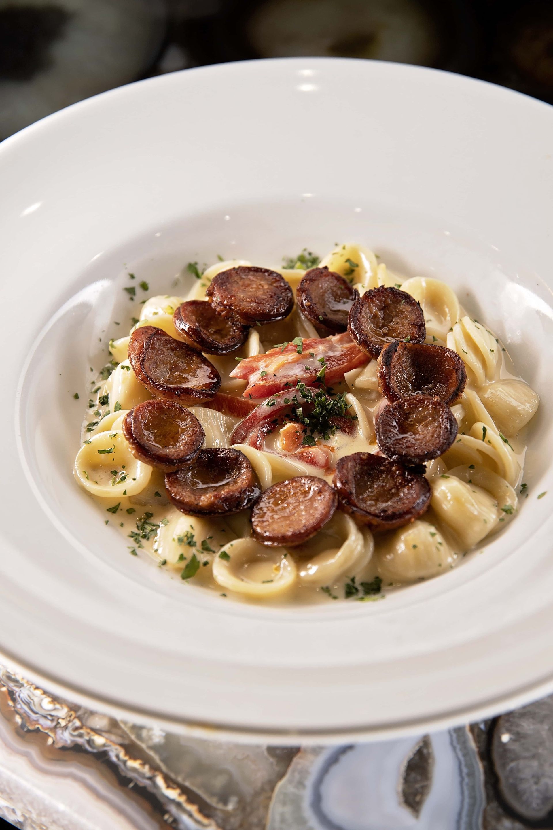 A white bowl filled with pasta and meat on a table.