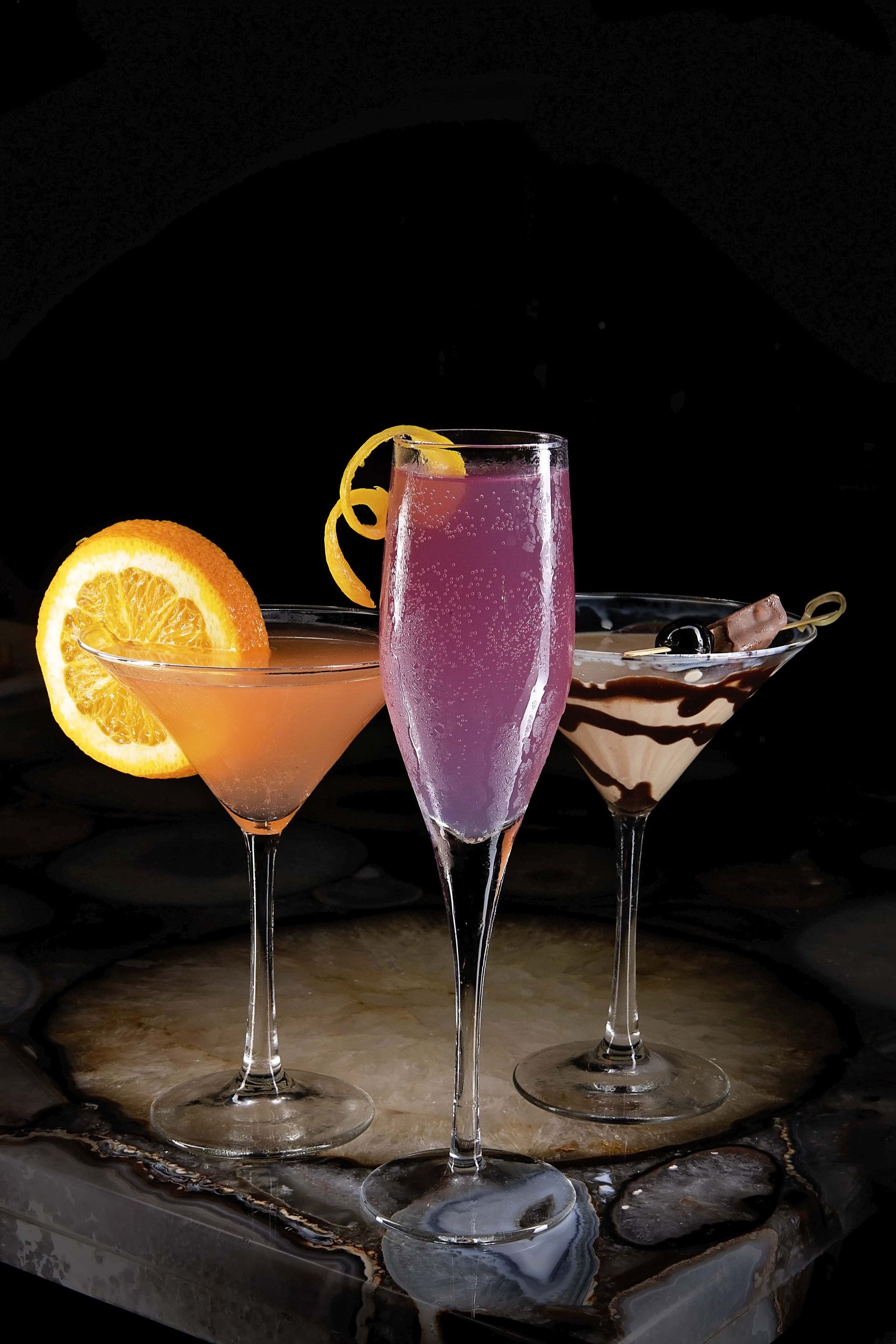 Three different types of cocktails are sitting on a wooden table.